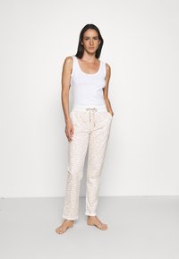 Witte katoenen tanktop, gecombineerd met lichtroze sweatpants met een subtiel zebrapatroon, een getailleerde tailleband en zijzakken.