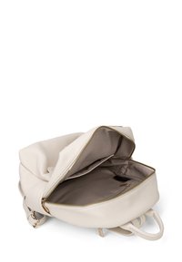 Zaino in pelle crema con una superficie testurizzata, una cerniera dorata e un compartimento aperto che rivela un interno beige e una piccola tasca.