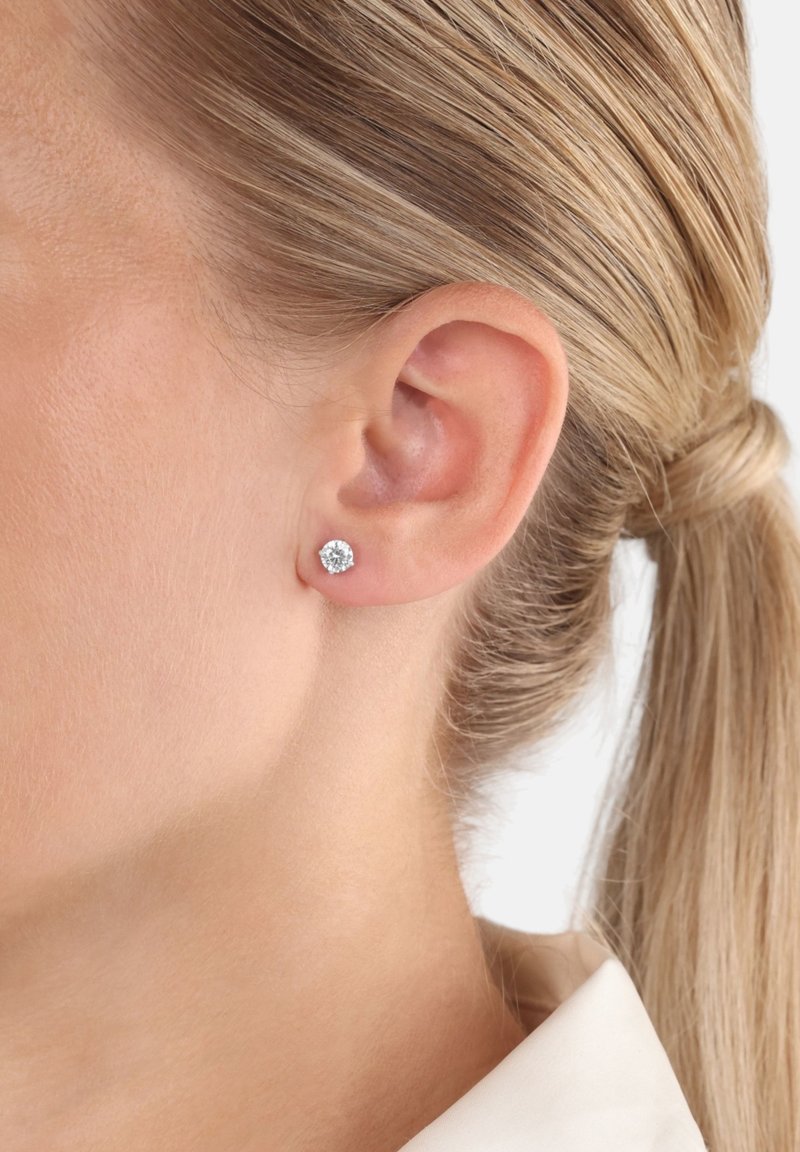 Runda cubic zirconia stuver i en silverfärgad inställning, med en enkel, polerad design. Klar och reflekterande yta, liten storlek.