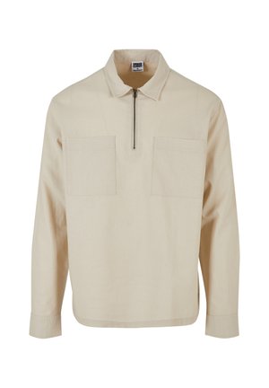 Beige Pullover-Oberteil aus strukturiertem Stoff, mit einem halben Reißverschluss, zwei Fronttaschen und langen Ärmeln mit geradem Saum.