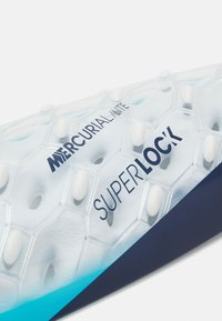 Mercurial Lite Superlock cleat sål i gennemsigtig hexagonal design med hvide accenter. Har tekstureret overflade og gradueret blå detalje.