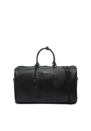 Sac de voyage en cuir noir avec doubles poignées, bandoulière détachable et étiquette à bagages, sur fond blanc uni.