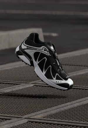 Mustmust ja hallid jooksujalad, millel on võrgust pealmine osa, kumer disain, peegeldavad detailid ning pehmendusega tald, millel on tekstuuriga mustrimuster.