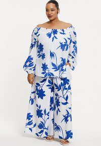 Blaue und weiße Blumen-Off-Shoulder-Bluse mit weiten Ärmeln, kombiniert mit passenden weiten Hosen; leichtes Material, entspannter Schnitt, Blumenmuster.