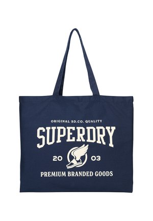 Marineblå tote taske med lange håndtag, med hvid tekst "Superdry," "2003," og "Premium Branded Goods" med en vingeformet sko logo.