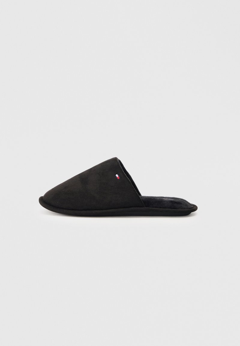 Zapatilla negra de tipo slip-on con puntera afilada, fabricada en suave ante y con un interior acolchado. Presenta un pequeño logo en el costado.