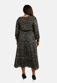 Svart blommig maxiklänning med långa ärmar, samlad halsringning och flerskiktad kjol. Har ett vitt blommönster och en figursydd midja.