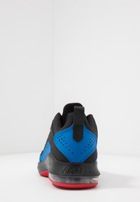 Zwarte en blauwe sneaker met een gestructureerde bovenkant, een rode zool en een achterste treklipje. Voorzien van perforaties voor ademend vermogen en AIRMAX branding.
