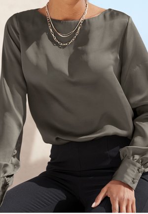 Dunkelolivgrüne Bluse mit hohem Ausschnitt, langen Ärmeln, geknöpften Manschetten und einer glatten, glänzenden Textur; mehrschichtige Kettenhalsketten fügen Details hinzu.