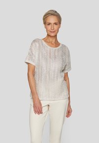 Silbernes, gestricktes T-Shirt mit kurzen Ärmeln und rundem Halsausschnitt, mit lockerer Passform und texturiertem Stoff. Kombiniert mit hellen Hosen.