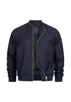 Marineblå bomberjakke med sølv lynlås delvist åben, ribstrikkede manchetter og kant samt to forlommer.