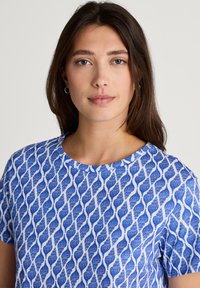 Blauwe en witte t-shirt met een golvende patroon. Korte mouwen, ronde halslijn en een gladde stoftextuur.