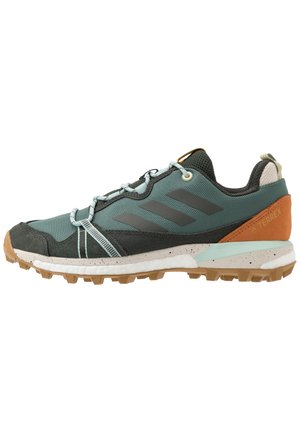 Udendørs vandresko med turkis stof, sort ruskind, brun hællap, lyseblå snørebånd, robust tan sål og Adidas tre-stribe logo på siden.