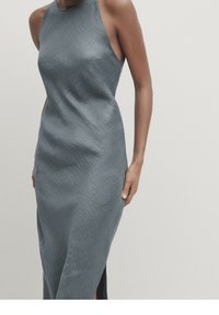 Robe grise sans manches avec une surface texturée, dotée d'un col haut et d'une fente sur le côté, créant une silhouette élégante et ajustée.