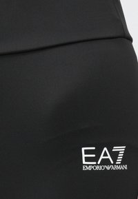 Fekete sportos leggings sima, rugalmas anyagból. Bal oldalon fehér EA7 logó az Emporio Armani-tól.
