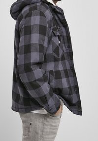 Svart och grå rutigt flanelljacka med huva, som har ett mjukt innerfoder, knäppning med knappar och sidofickor.