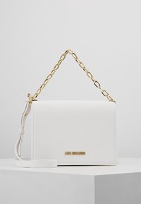 Vit konstläder handväska med en guld kedjeslinga, rektangulär form och en guld logotypaccent framtill. Slät textur, minimalistisk design.