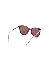 Gafas de sol carey con lentes marrones y detalles metálicos. Montura circular con brazos delgados y transparentes. Acabado pulido.