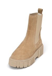 Bottine en suédine beige avec des panneaux latéraux en élastique, semelle plateforme épaisse surélevée, et une languette à l'arrière pour un enfilage facile.
