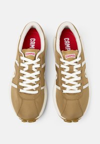 Sneakers con lacci in tessuto marrone chiaro con accenti bianchi. Punta arrotondata, collo imbottito, soletta rossa e suola in gomma.