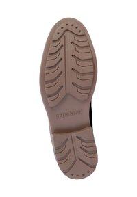 Black sneaker sole with a textured light brown rubber bottom, featuring a zigzag tread pattern and the brand name “REDSKINS” embossed.