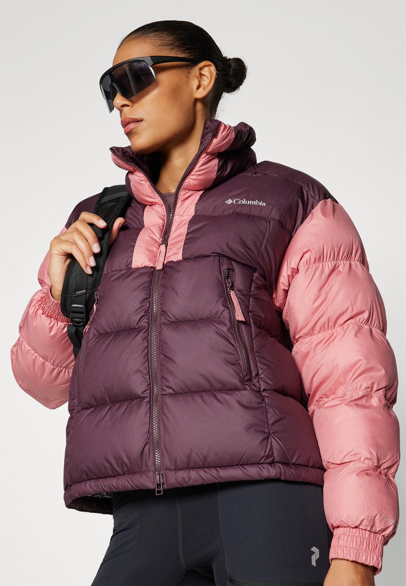 Giacca bomber con una combinazione di colori viola e rosa, dotata di chiusura con zip, colletto alto e logo. Texture liscia con polsini elasticizzati.