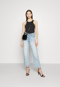 Svart ermeløs topp, lyseblå vid ben jeans, svart crossover veske, svarte heels med stropper. Minimalistisk design med en uformell stil.