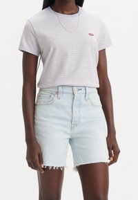 Randig t-shirt i ljusblått och vitt, med korta ärmar och rundad halsringning, kombinerad med ljusblå denimshorts med fransade kanter.