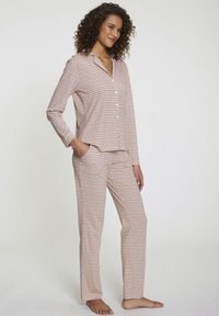Set di pigiama in cotone di colore corallo e bianco con un motivo geometrico; maglietta a maniche lunghe, chiusura con bottoni e pantaloni dritti abbinati con tasche.