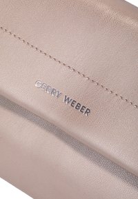 Bežna usnjena denarnica z teksturirano površino, ki ima šivane detajle in srebrno oznako "GERRY WEBER". Kompaktna in pravokotna oblika.