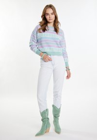 Pulover iz pletene tkanine s pastelnimi vzorci v modri, roza in zeleni barvi, v kombinaciji z belimi kavbojkami in zelenimi suede čevlji v cowboy slogu s perforiranimi detajli.