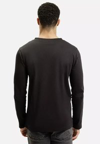 Czarna koszulka z długim rękawem o okrągłym dekolcie, gładka w dotyku i dopasowane rękawy, pokazana z tyłu, połączona z ciemnymi dżinsami.