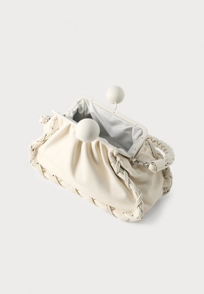 Sac à main couleur crème avec détails tressés, tissu doux, boutons ronds de fermeture et doublure intérieure rayée.