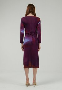 Vestido de manga larga en un morado profundo con patrones abstractos en azul y naranja. La tela parece ligera con un corte holgado y aberturas laterales.