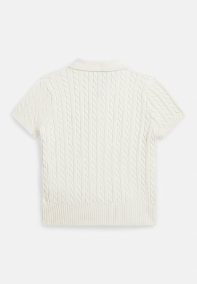 Polo sveter s krátkym rukávom v krémovej farbe, s pletenou textúrou a rebrovaným lemom a golierom. Vyrobený z mäkkého pleteného materiálu.