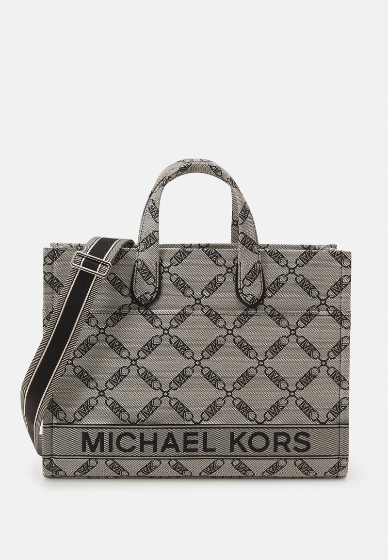 Sac cabas gris Michael Kors avec motif chaîne noire, doubles poignées et bandoulière noire réglable avec rayures blanches.