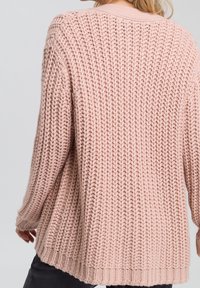 Maglione lavorato a maglia rosa chiaro con vestibilità ampia, caratterizzato da un motivo testurizzato e spesso e orlo a coste. Maniche lunghe e scollatura a girocollo.