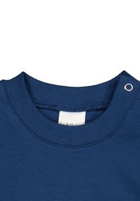 Dunkelblaues Baumwoll-Sweatshirt mit Rundhalsausschnitt, einem gerippten Kragen, einem Druckknopfverschluss an der Schulter und einem gewebten Etikett am Kragen.