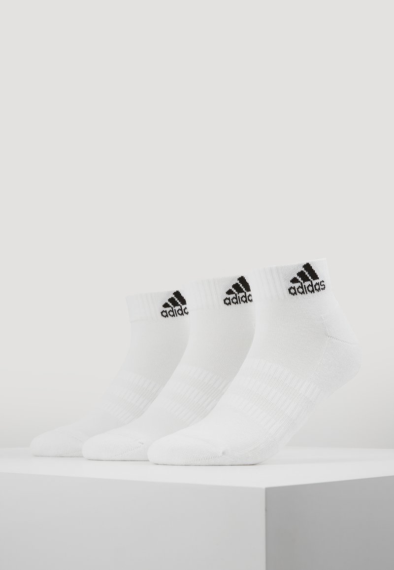Tres pares de calcetines tobilleros blancos con el logo negro de Adidas en el puño, con textura acanalada y rayas horizontales para un mejor agarre.