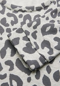 Tessuto grigio con stampa leopardata, caratterizzato da un collo rotondo e maniche piegate, che mette in evidenza una texture morbida e macchie scure a contrasto.