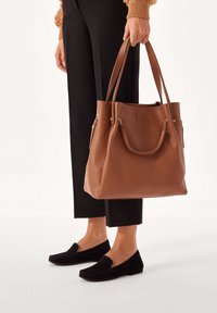 Bruine lederen tote bag met een gestructureerd patroon, voorzien van dubbele handvatten, gouden hardware accenten en een grote opening aan de bovenkant.