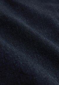 Ciemnoniebieska tkanina o fakturze z drobnymi wzorami tkackimi i miękkimi fałdami, tworzącymi subtelne cienie i refleksy świetlne.