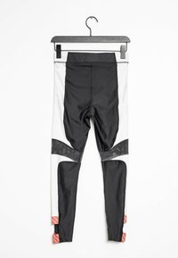 Mustat ja valkoiset urheilulegginsit, joissa on verkkomaisia yksityiskohtia. Ne ovat korkean vyötärön ja istuvat hyvin, ja lahkeensuissa on raidalliset korallivärit.