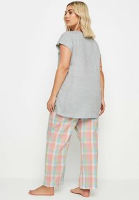 Grijze T-shirt met korte mouwen gecombineerd met pastelgeruite pyjamabroek in blauwe, roze en groene vierkanten; comfortabele pasvorm; zachte stof.