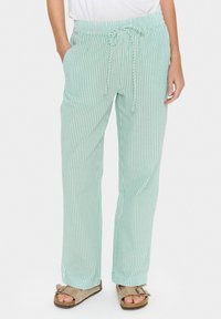 Pantalon rayé vert clair avec une taille élastique et un cordon de serrage, disposant de poches latérales et d'une coupe ample pour plus de confort.