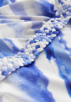 Blue and white patterned fabric featuring a braided trim with interwoven textures, presenting a smooth surface and watercolor-like design.