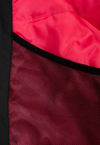 Schwarzer Netzstoff überlagert einen glatten rosafarbenen Futterstoff und zeigt eine kontrastierende Textur- und Farbkombination mit einem sauberen Rand.