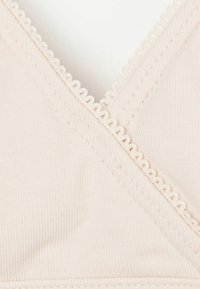 Bralette rose clair avec un décolleté en V, en tissu texturé, avec des bords festonnés et un matériau souple et extensible.