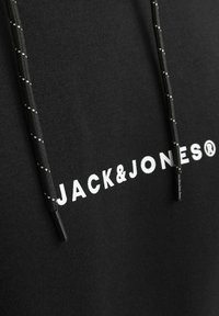 Crna dukserica s bijelim logotipom "JACK&JONES". Ima teksturirani materijal, vezice s crnim i bijelim naglascima, te klasičan kroj.