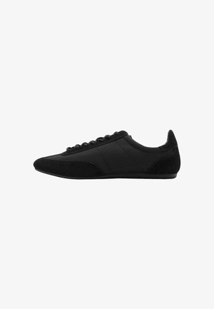 Scarpe sportive nere caratterizzate da una combinazione di materiali lisci e testurizzati, un design a profilo basso e un classico sistema di allacciatura.